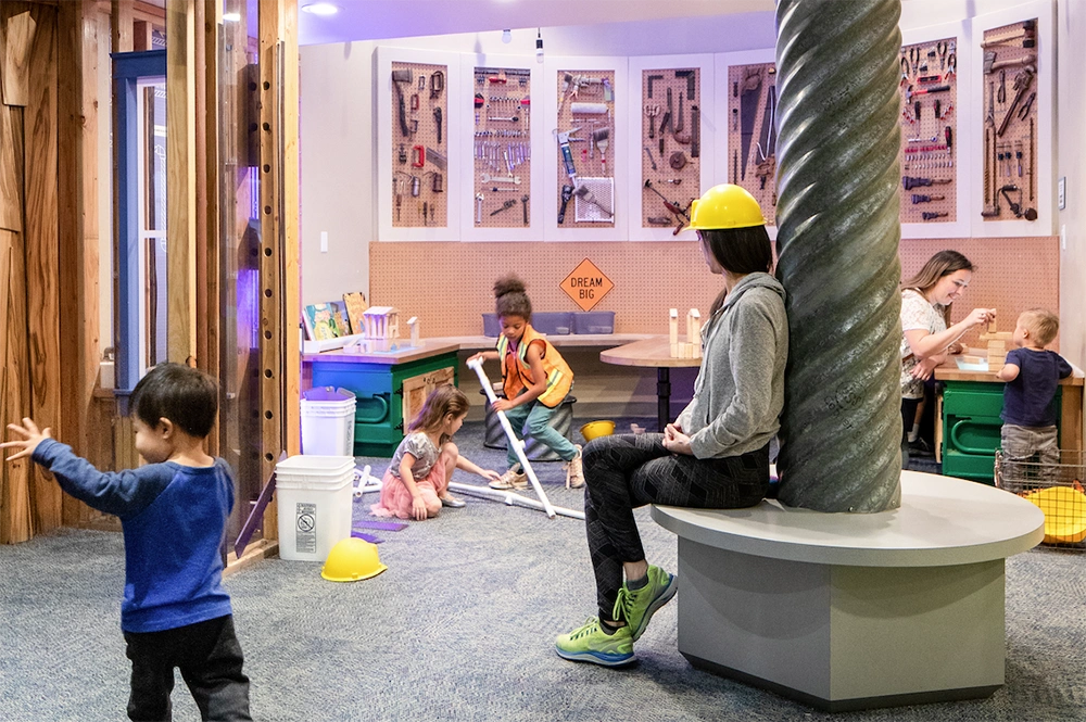 Niños y tutores jugando en la Galería de la Ciencia y la Imaginación, exposición Ferretería de Tuercas y Tornillos